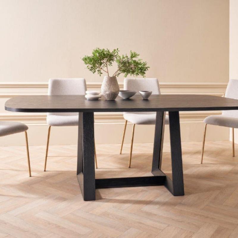 Dining table with chairs in a room with beige walls and wooden floor.