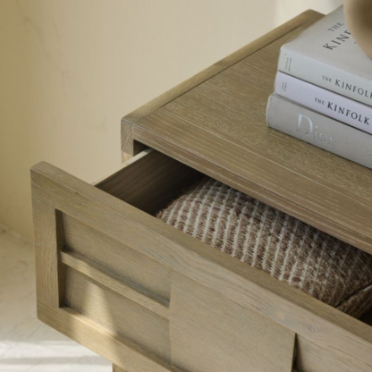 Wooden drawer with a stack of books on top against a beige background