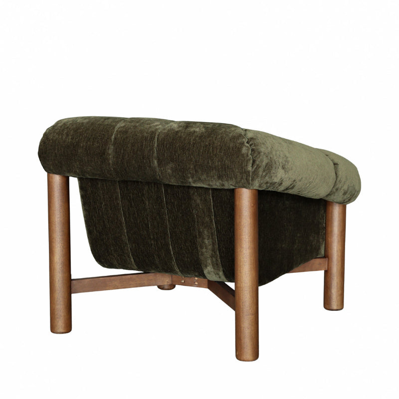 An upholstered accent chair with a dark olive green velvet seat and back, supported by four tapered metallic bronze legs and a matching bronze footrest bar, shown on a plain white background.