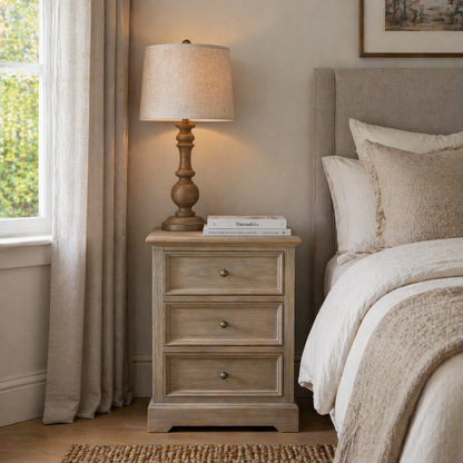 Nighstand with lamp and books next to a bed in a bedroom