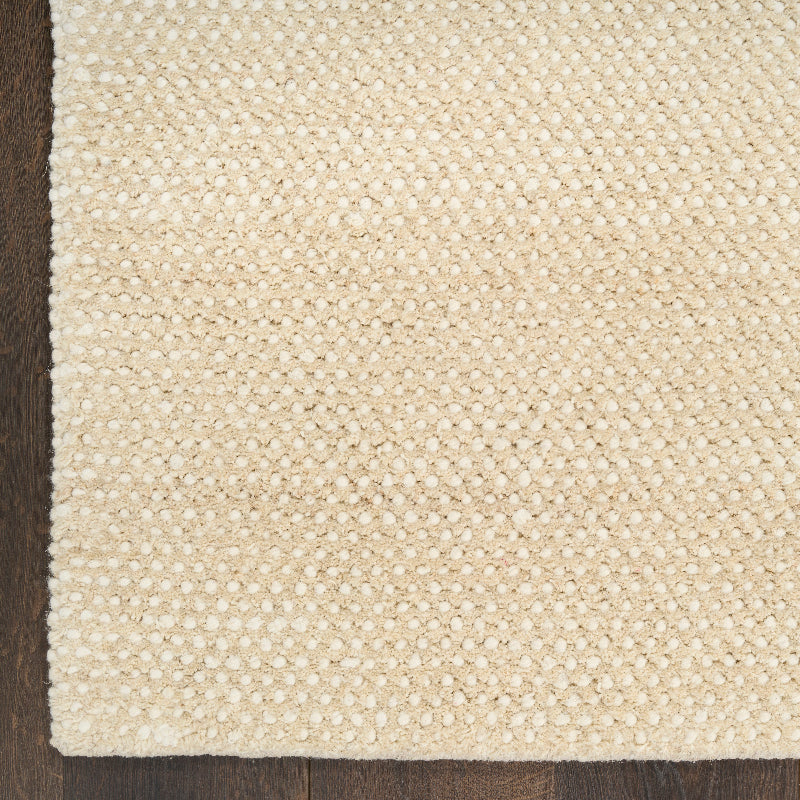 Close-up of a textured beige rug on a wooden floor