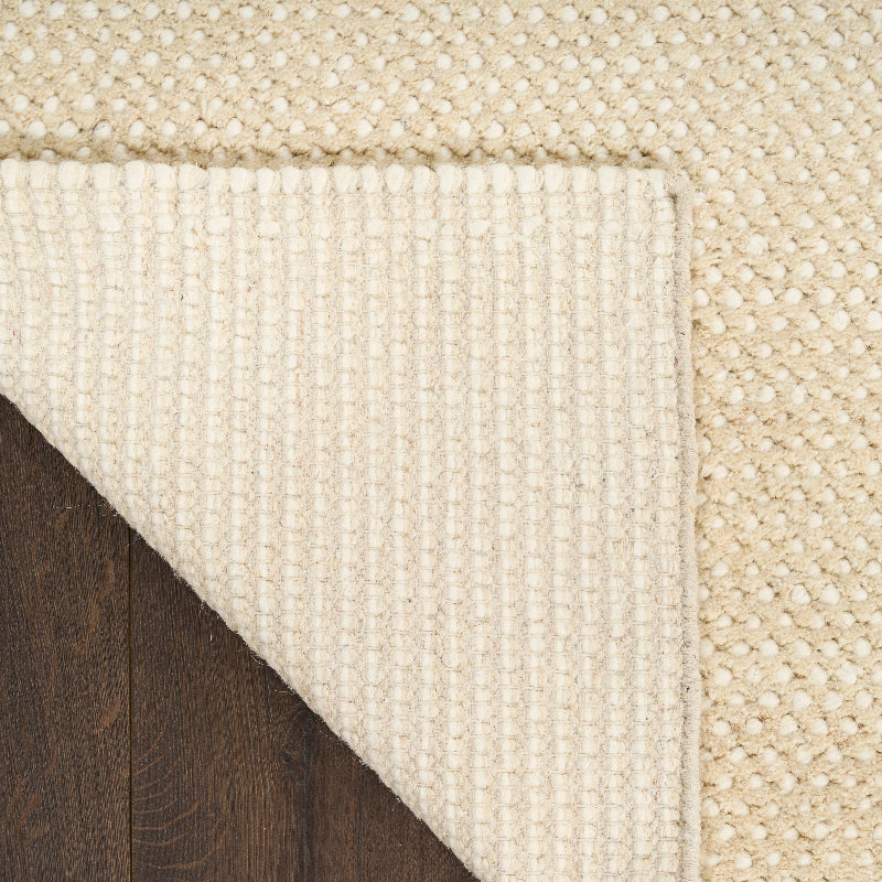 Close-up of a textured beige rug on a wooden floor