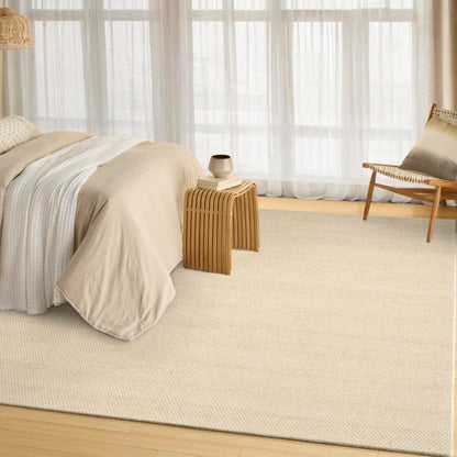 Beige bedroom with a bed, side table, and chair near large windows.