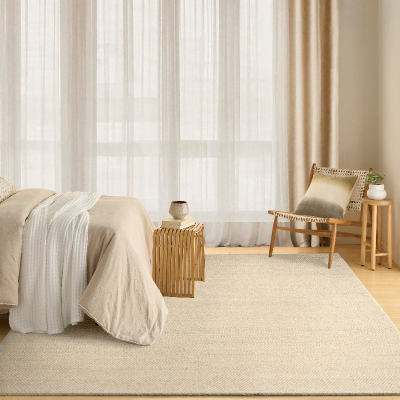 Beige bedroom with a bed, chair, and side table.