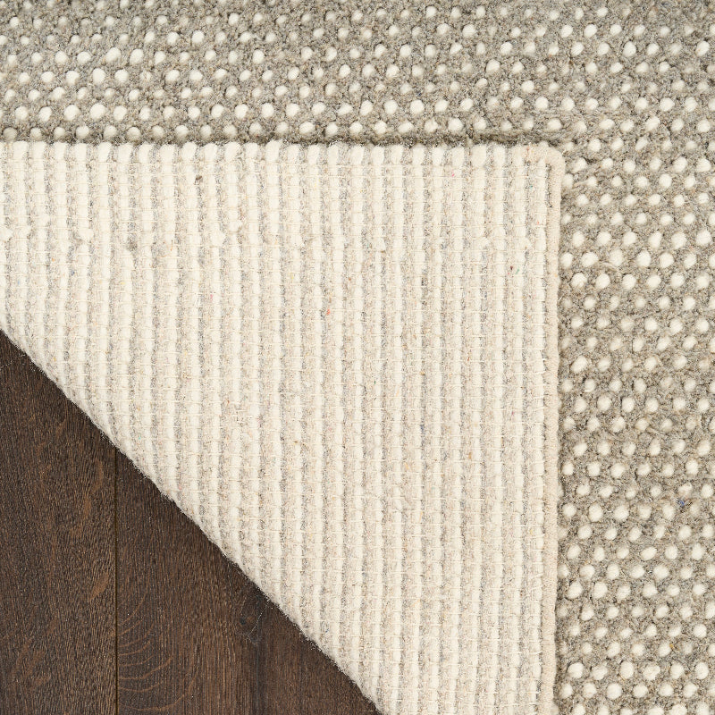 Close-up of a textured rug with a geometric pattern on a wooden floor.