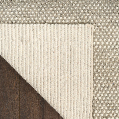 Close-up of a textured rug with a geometric pattern on a wooden floor.