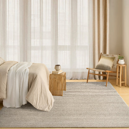 Modern bedroom with a grey ivory rug, bed, and chair.