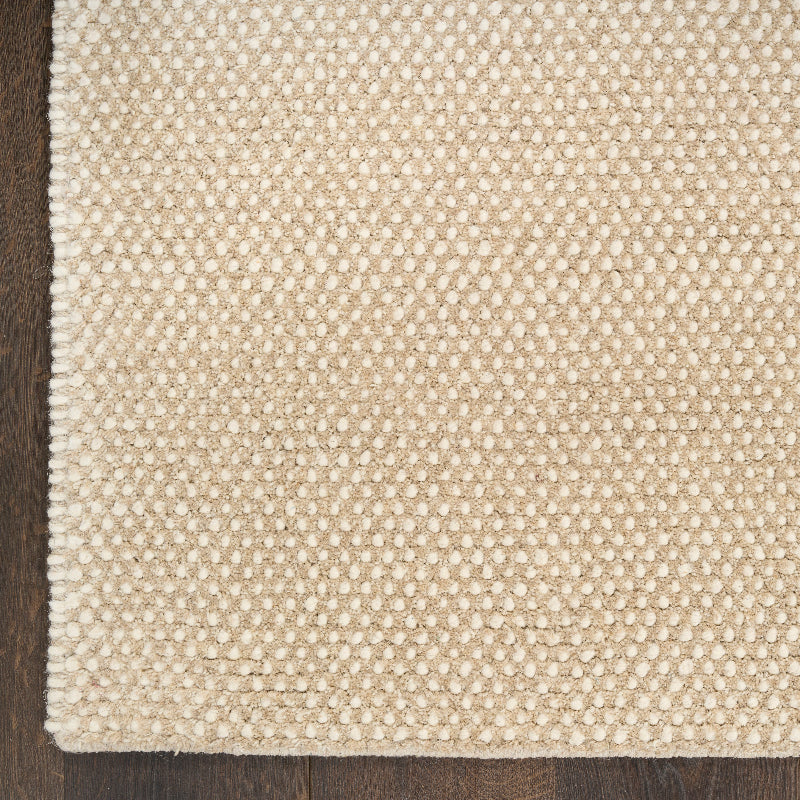 Close-up of a textured beige rug on a wooden floor