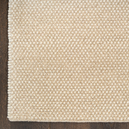 Close-up of a textured beige rug on a wooden floor