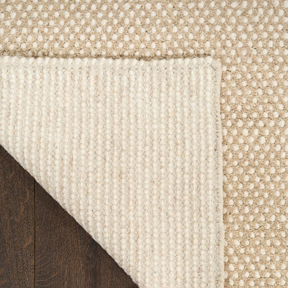 Close-up of a beige and white textured rug corner.