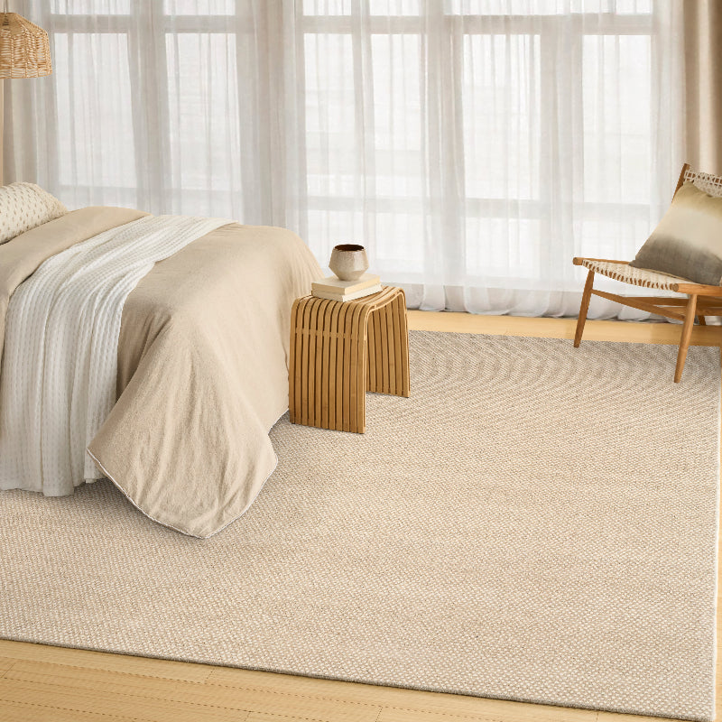 Beige bedroom with a bed, nightstand, and chair on a beige carpet.