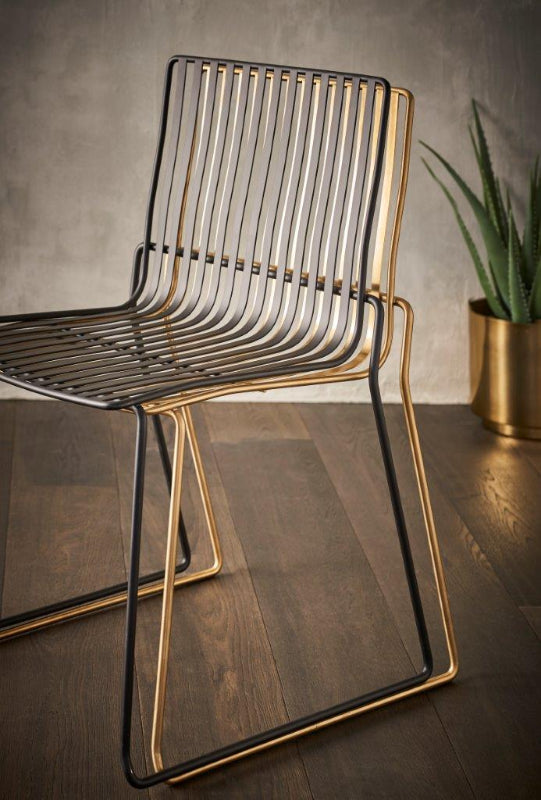 Modern chair with gold frame and black seat on a wooden floor.