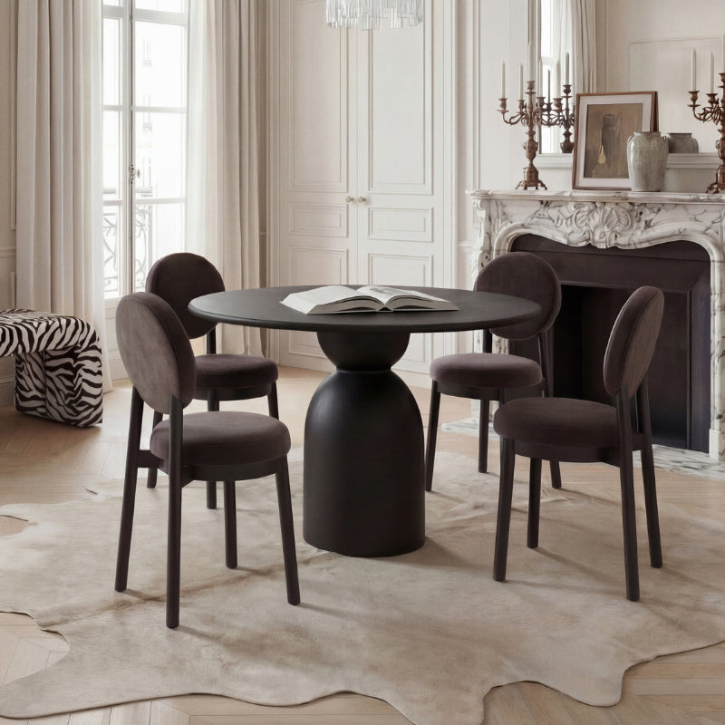 Dining room with a round black table and chairs in a stylishly decorated room.