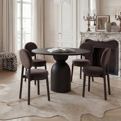 Dining room with a round black table and chairs in a stylishly decorated room.