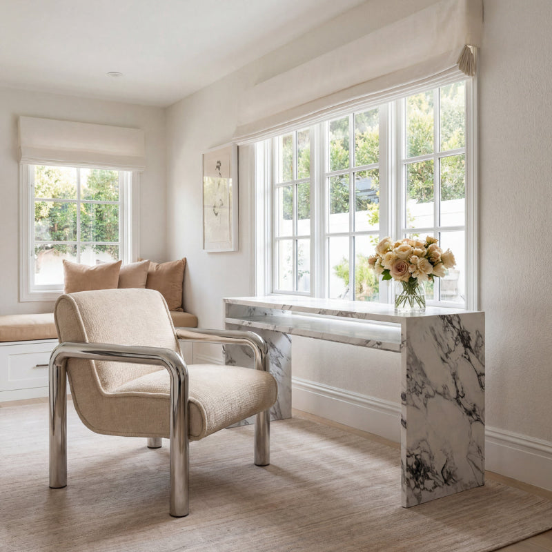 Modern interior with a beige armchair, marble desk, and large windows.