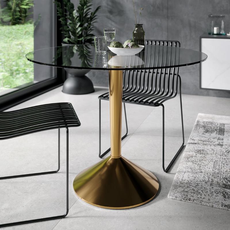 Modern dining table with gold pedestal base and black chairs in a room with large windows.