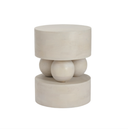 A modern sculptural side table or stool made of a light beige stone or concrete, featuring a top cylindrical platform supported by three rounded spherical forms in the middle, and a wider cylindrical base below, set against a plain white background.