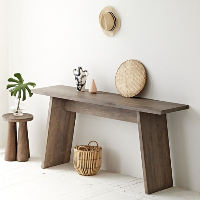 Wooden console table with decorative items against a white wall