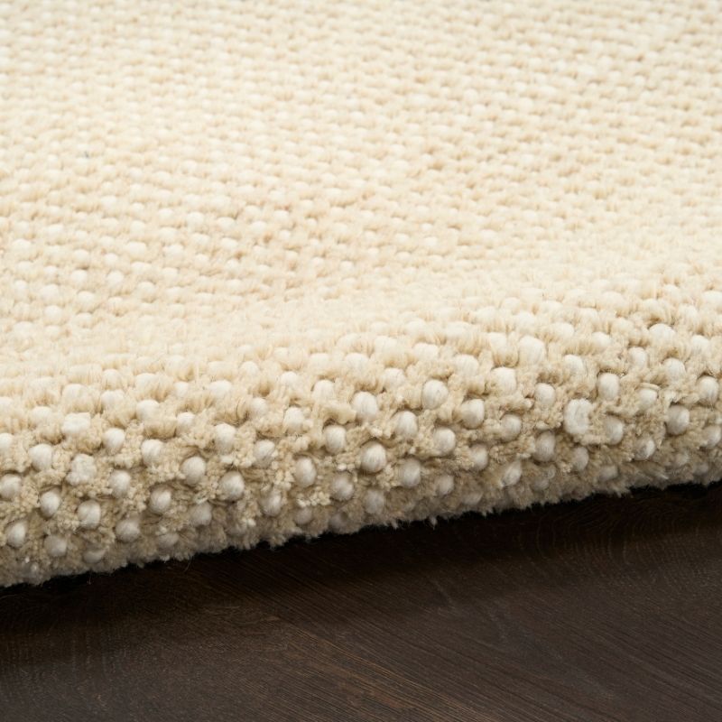 Close-up of a textured beige rug on a wooden floor