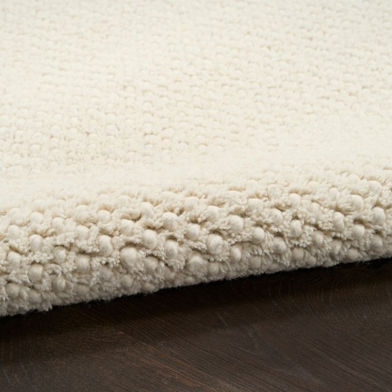 Close-up of a textured beige rug on a wooden floor