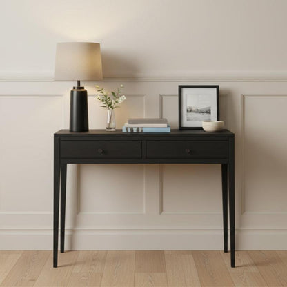 Black console table with decorative items against a neutral wall.