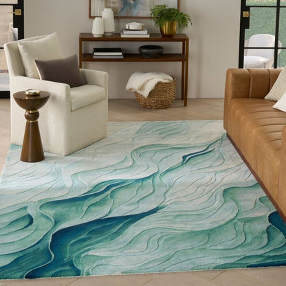 A modern area rug with an abstract wavy pattern in shades of teal, blue, and white, styled in a contemporary living room setting.