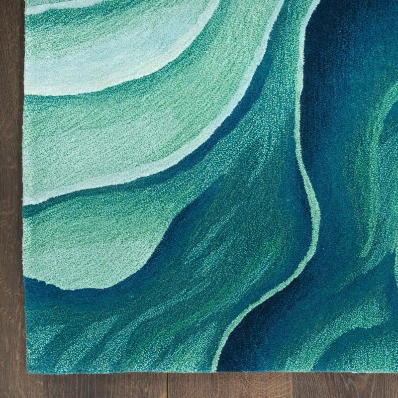 Teal and green abstract patterned rug on a wooden floor