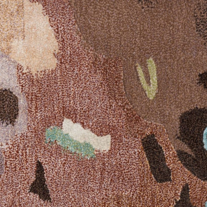A close-up of a textured area rug with an abstract, organic pattern in shades of brown, beige, black, and soft green.