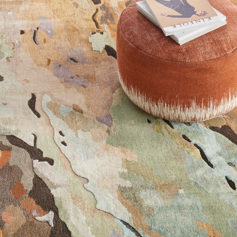 Camouflage-patterned rug with a brown ottoman and a book on top.
