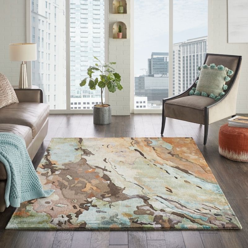 Living room with a colorful rug, sofa, chair, and plant.