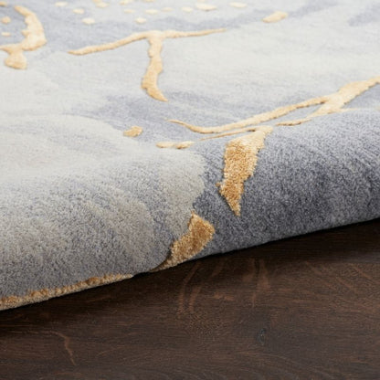 Close-up of a textured gray rug with gold leaf patterns on a wooden floor.