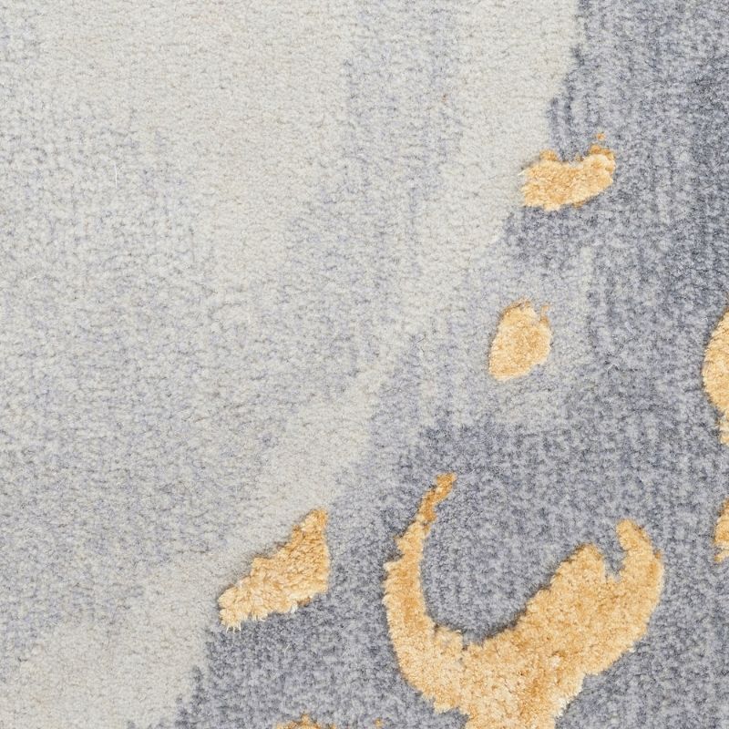Close-up of a plush area rug with a textured abstract pattern in light gray, medium gray, and beige.