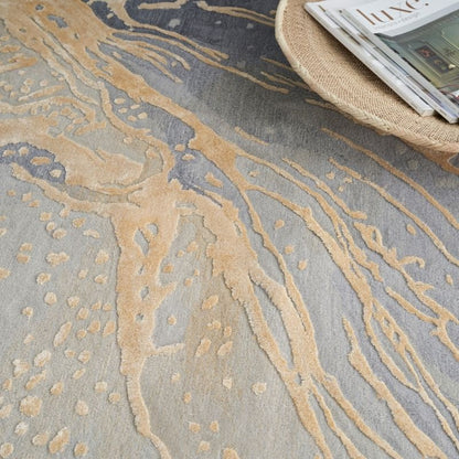 Close-up of a textured rug with gold and gray patterns, featuring a woven basket and books in the corner.