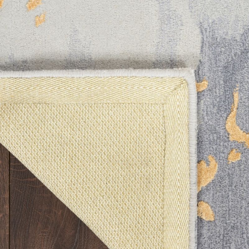 Close-up of a corner where two rugs meet, one beige and one gray with gold patterns.