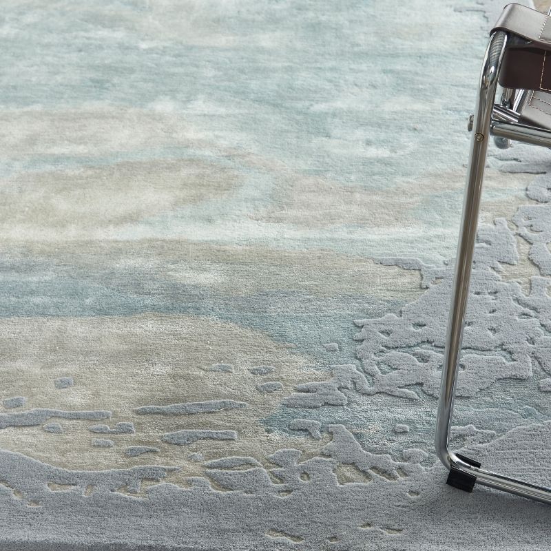 Close-up of a textured gray rug with a chair leg partially visible