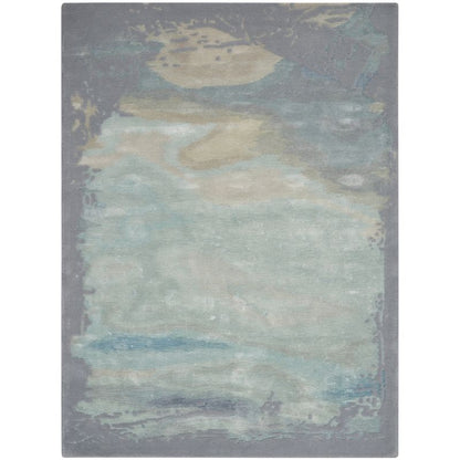 An abstract area rug with a distressed, painterly design in muted shades of gray, teal, beige, and blue, shown flat against a white background.