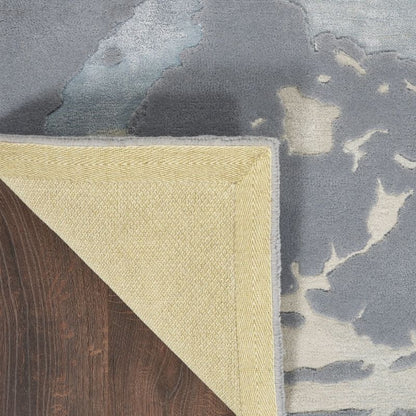 Close-up of a textured rug corner with a floral pattern on a wooden floor.