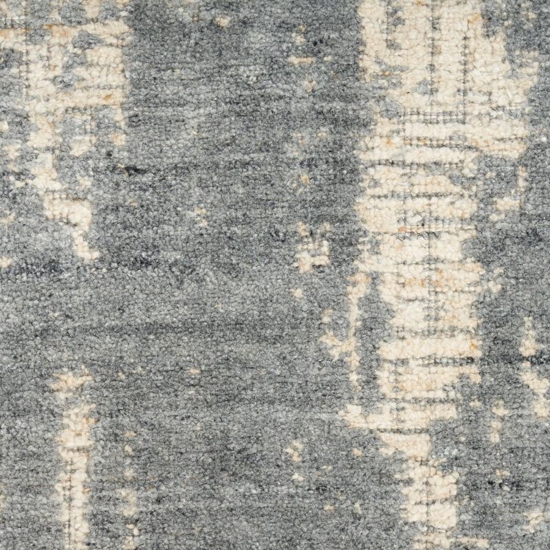 A close-up of a textured area rug with a distressed, vintage pattern in shades of gray, beige, and off-white.