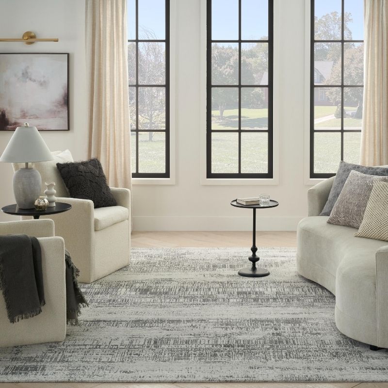 Living room with beige sofa, armchair, and coffee table in front of large windows.