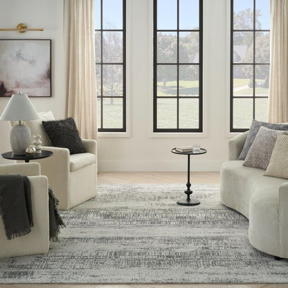Living room with beige sofa, armchair, and coffee table in front of large windows.