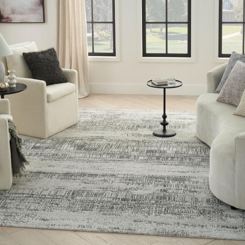 Living room with a patterned rug, white chairs, and side tables.