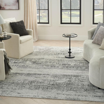 Living room with a patterned rug, white chairs, and side tables.