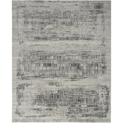 A rectangular area rug with a distressed, abstract pattern in shades of gray, beige, and off-white.