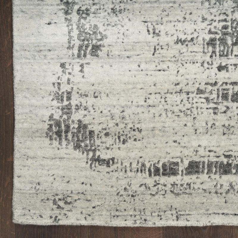 Textured area rug with a mix of gray and black patterns on a wooden floor.