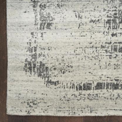 Textured area rug with a mix of gray and black patterns on a wooden floor.