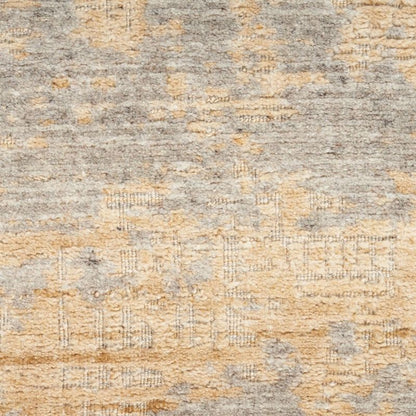 A close-up of a textured area rug with a distressed, abstract pattern in warm beige, tan, and light gray.