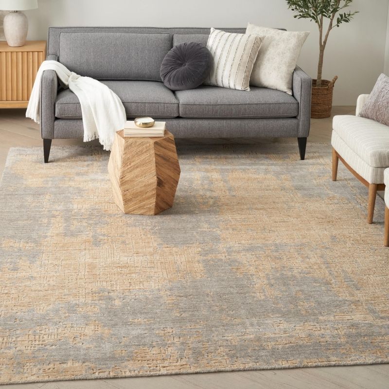 Living room with a gray sofa, wooden side table, and patterned rug.