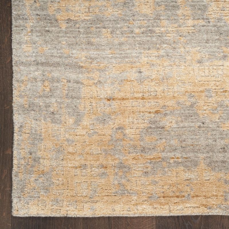 Textured area rug with a mix of gray and beige colors on a wooden floor.