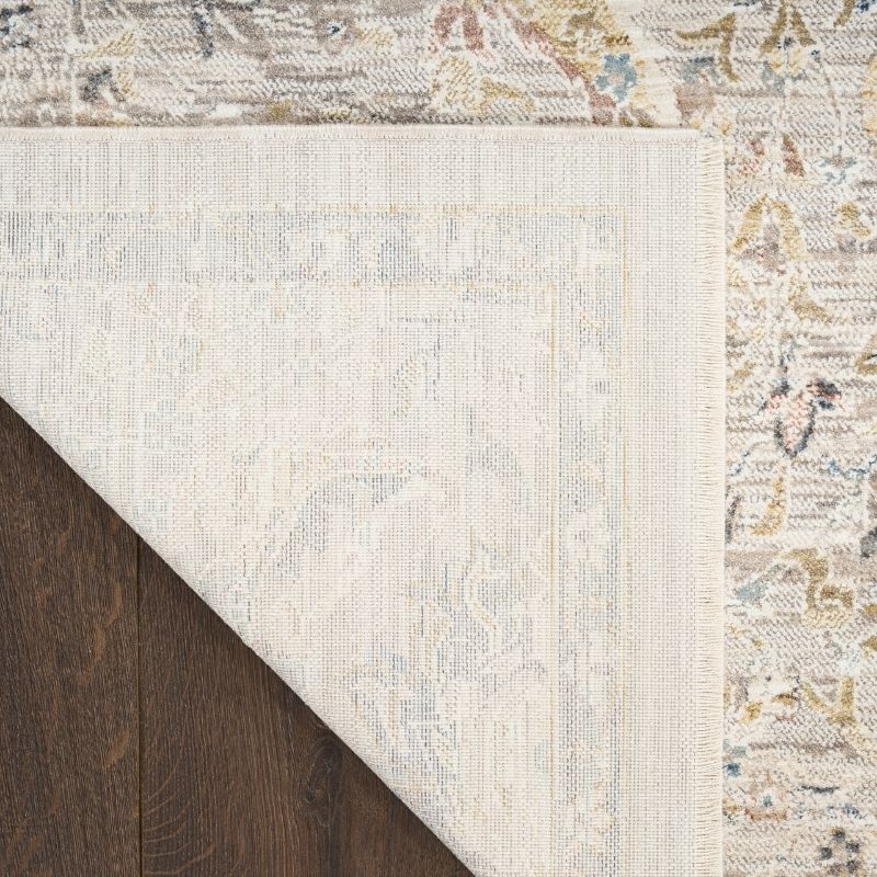 Close-up of a textured area rug with a border on a wooden floor.