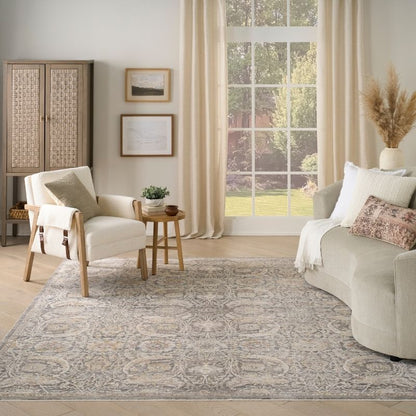 Living room with beige sofa, armchair, and side table on a patterned rug.